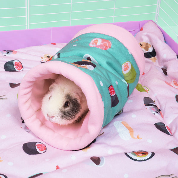 cochon d'inde caché dans un tunnel rose et bleu turquoise aux motifs sushi dans une cage sur un tapis polaire