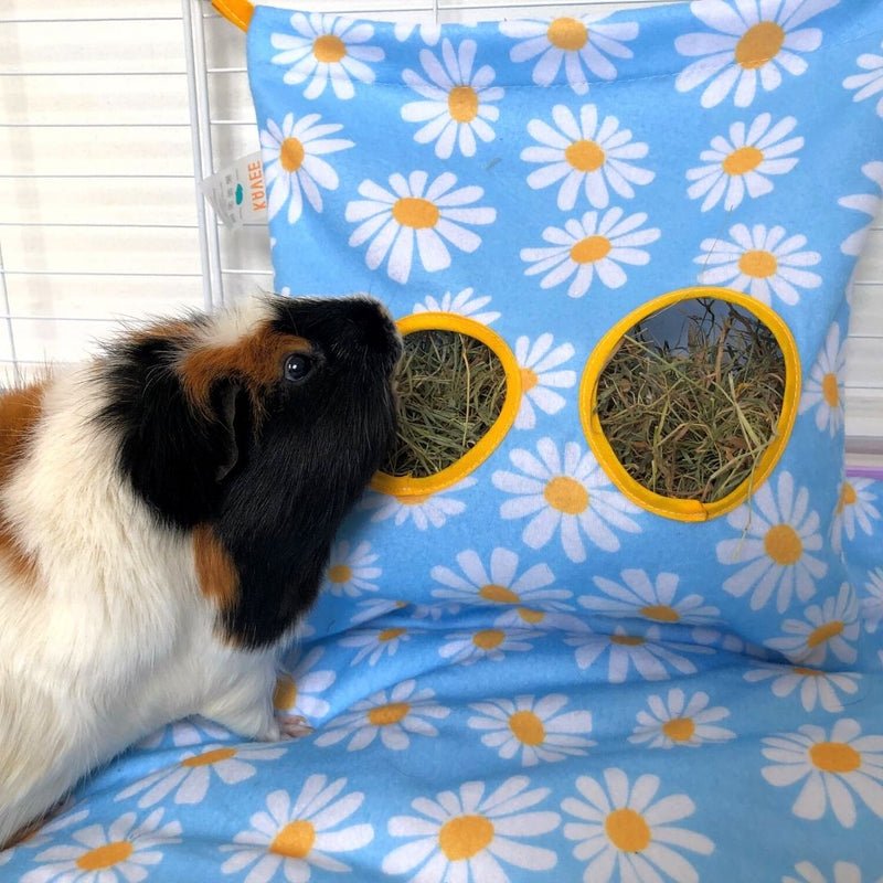 tri colored guinea pig eating timothy hay out of the daisy fleece hay bag