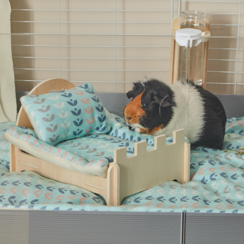 Cochon d'Inde tricolore s'appuyant sur un lit en bois avec coussin et Pee pad en polaire bleu nature nordique pour cochon d'inde par kavee